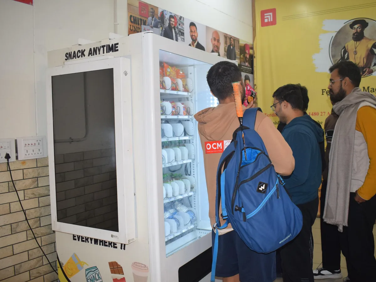 Confident operator standing beside a vending machine on a busy Indian college campus