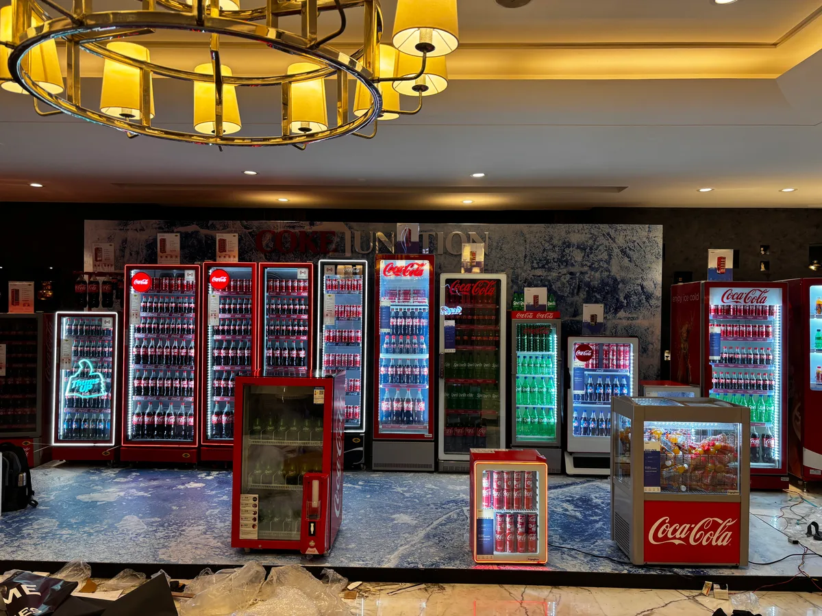 Still life of a vending machine model, a canned drink and stacks of rupee notes and coins