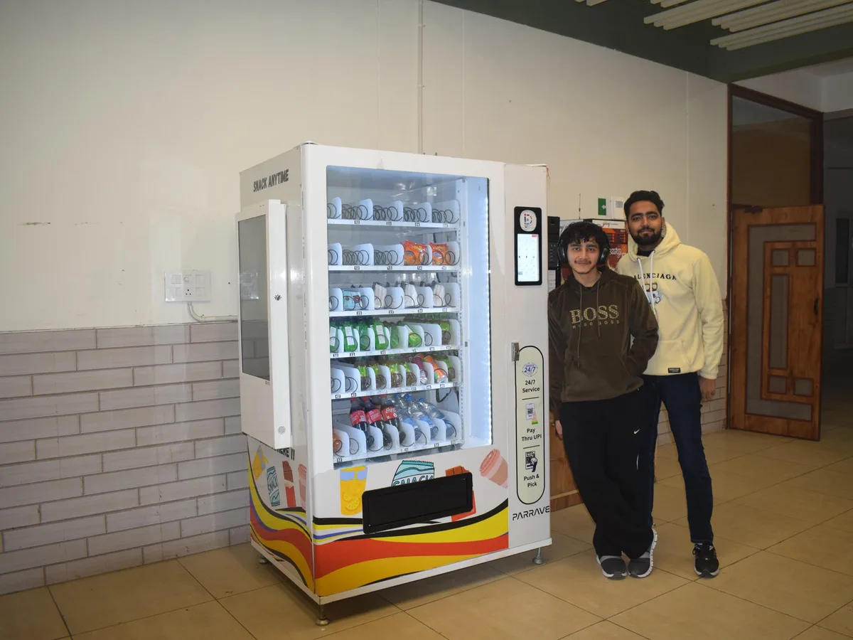 Neglected vending machine in a dim, empty stairwell corner with no customers