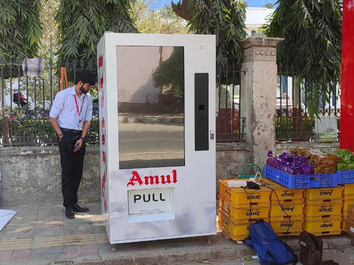Two book vending machine models in a showroom with a buyer inspecting one
