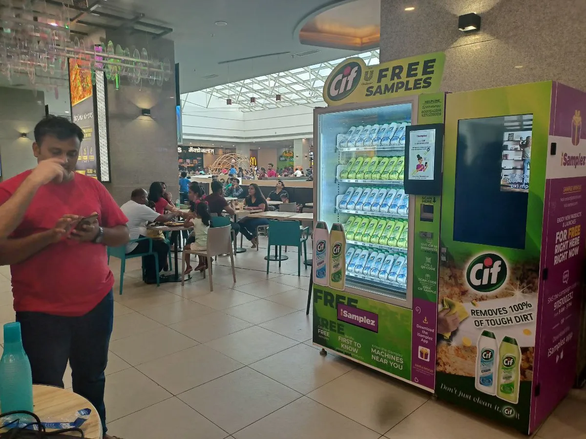 Installer smoothing a vinyl wrap onto a vending machine panel with a squeegee