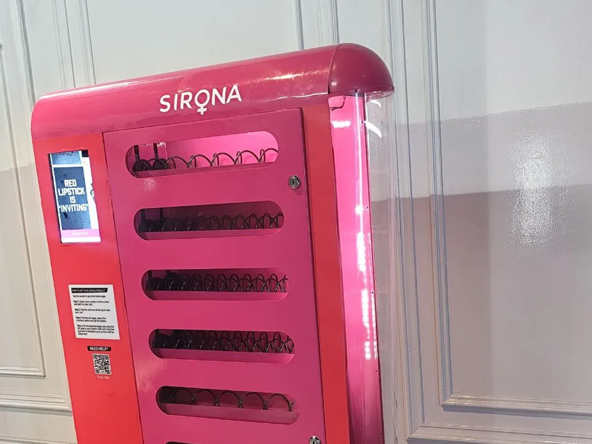 Hand holding a prepaid gift card near the card reader of a vending machine