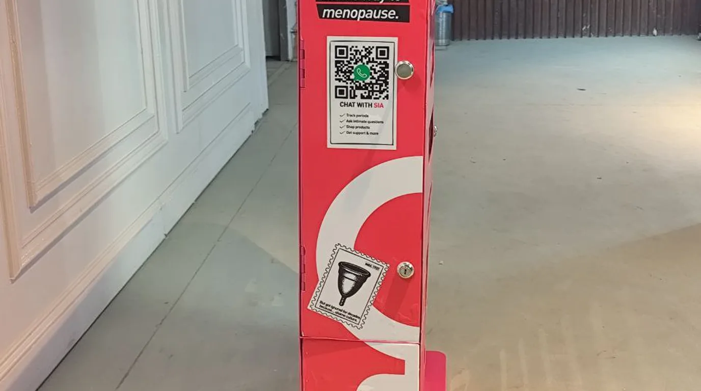 Busy cashless vending machine with customers tapping to pay and a rising-sales screen nearby