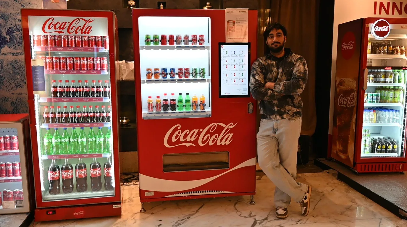 Vending operator with a tablet checklist standing next to a modern vending machine