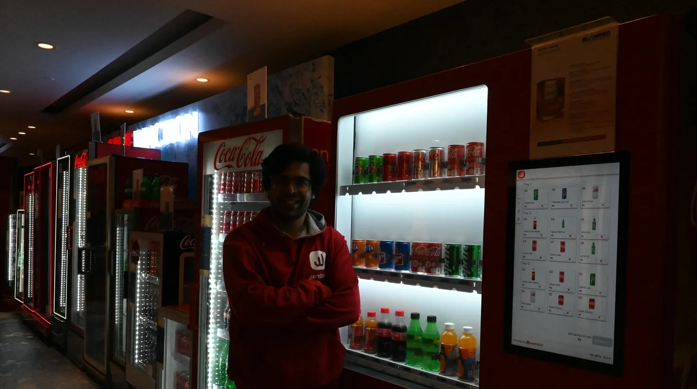 Entrepreneur with a phone standing beside a single modern vending machine