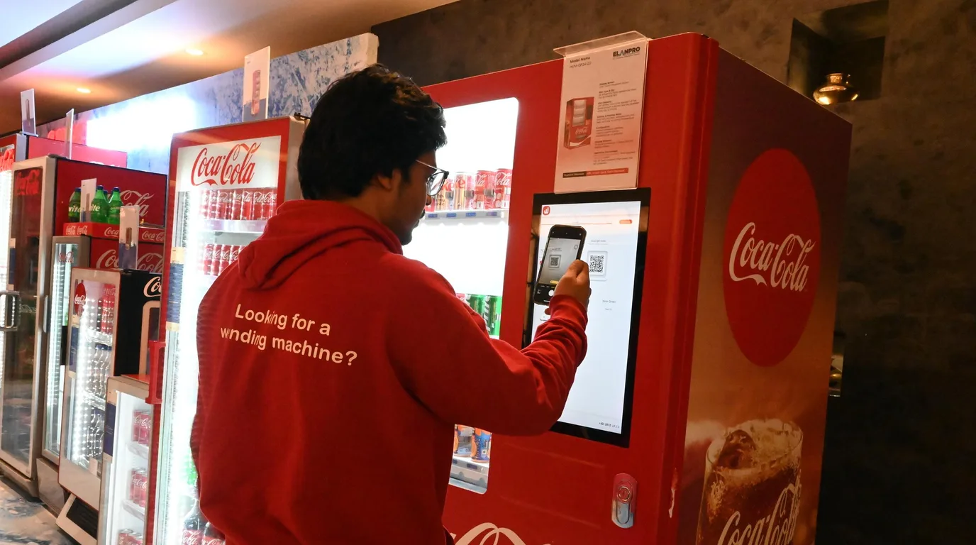 Model vending machine beside a face-down price tag and coins suggesting hidden cost