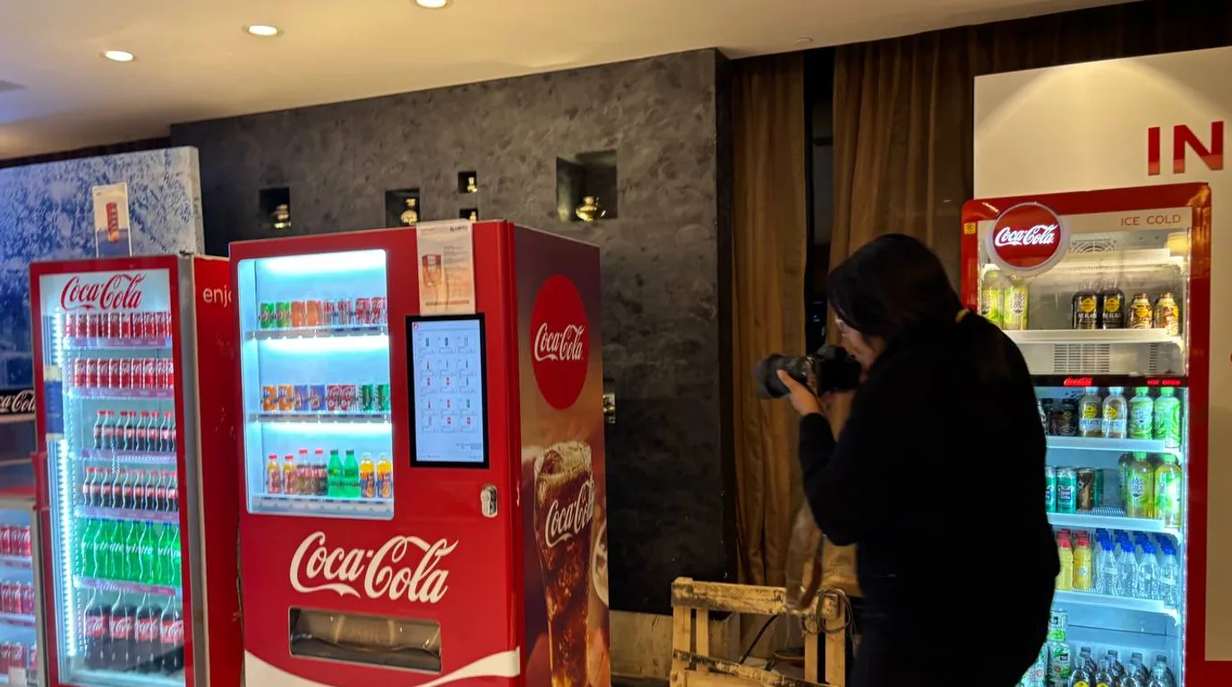 Proud Indian vendor standing beside a compact modern vending machine