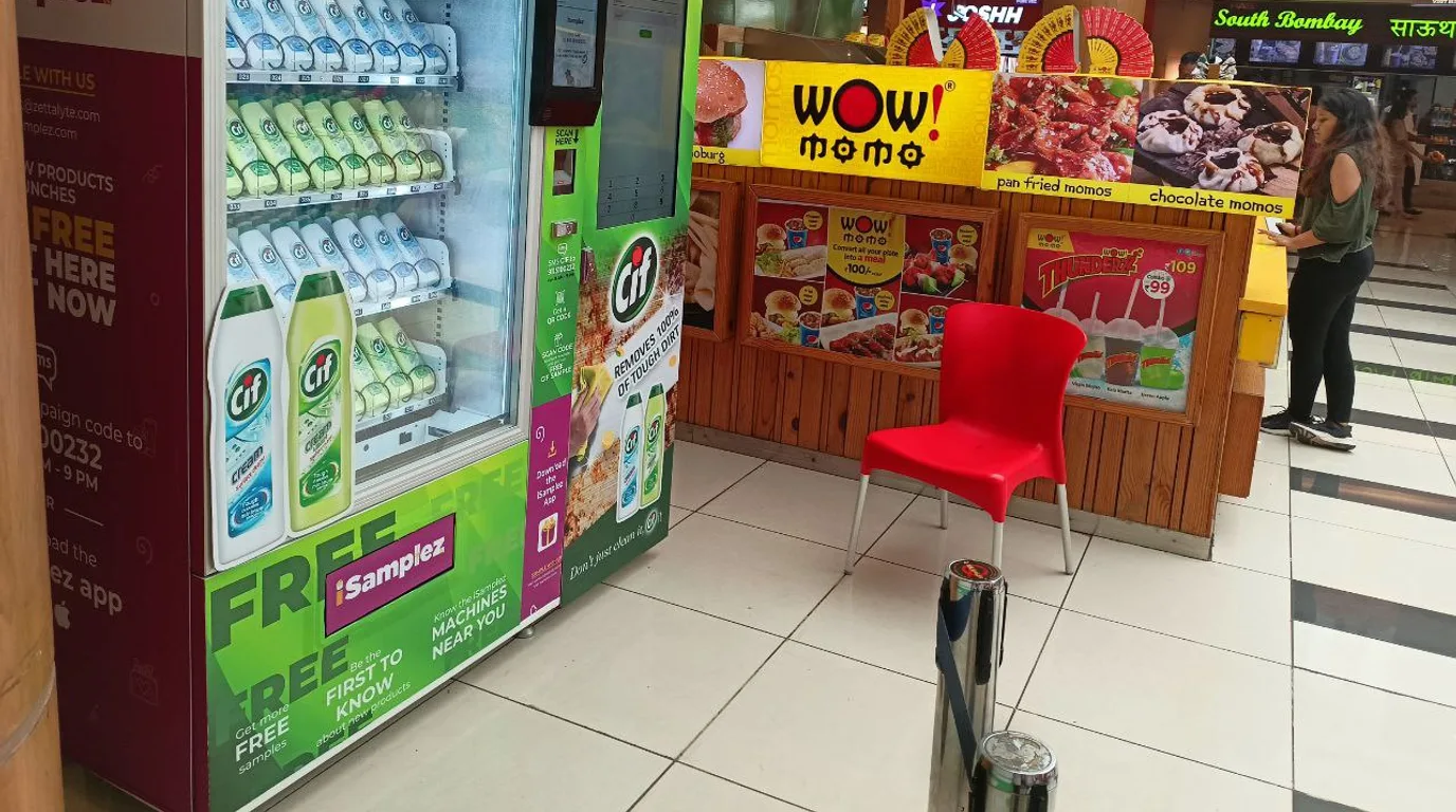 Vending machine at a busy transit hub entrance with crowds streaming past