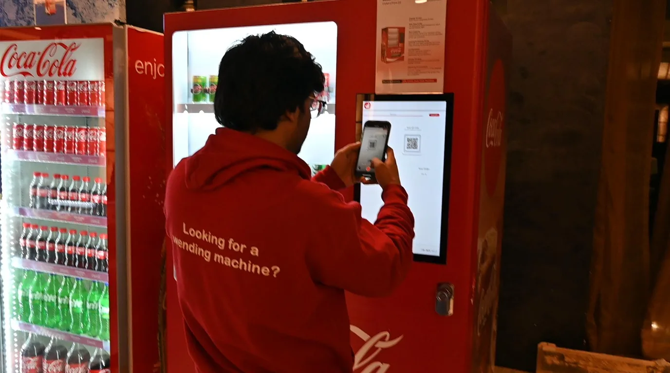 Operator planning a vending business budget at a desk with a model machine and card reader