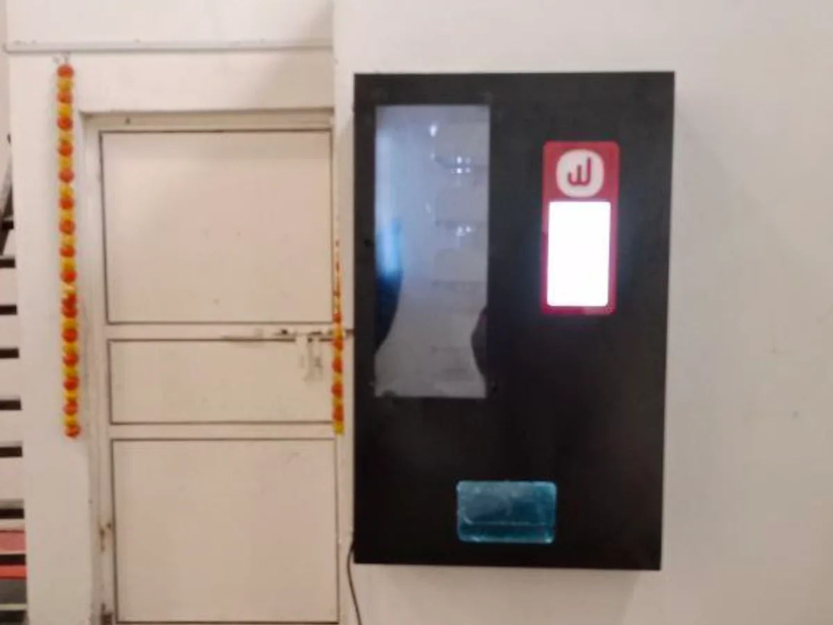 Electrician plugging a vending machine into a dedicated power socket near a circuit breaker.