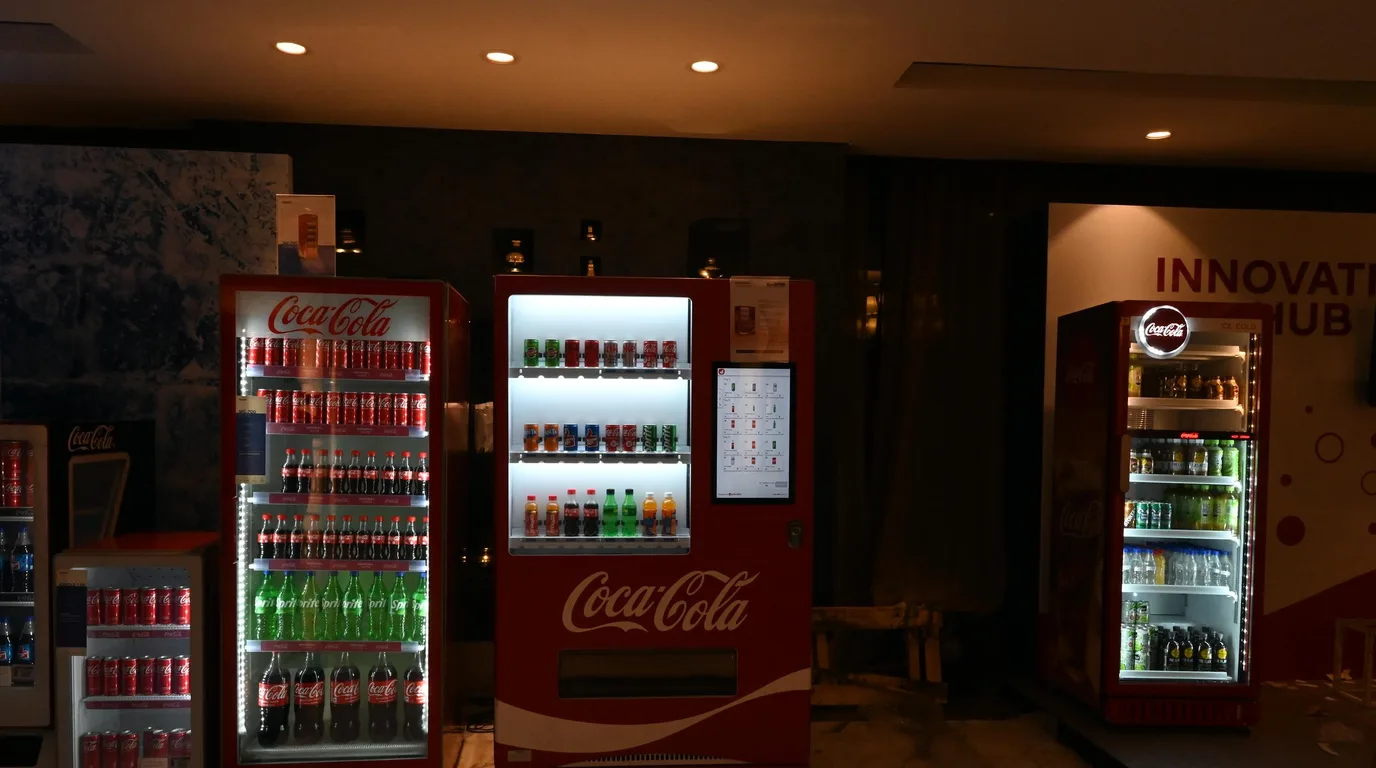 Operator updating vending machine prices remotely on a phone and laptop dashboard.