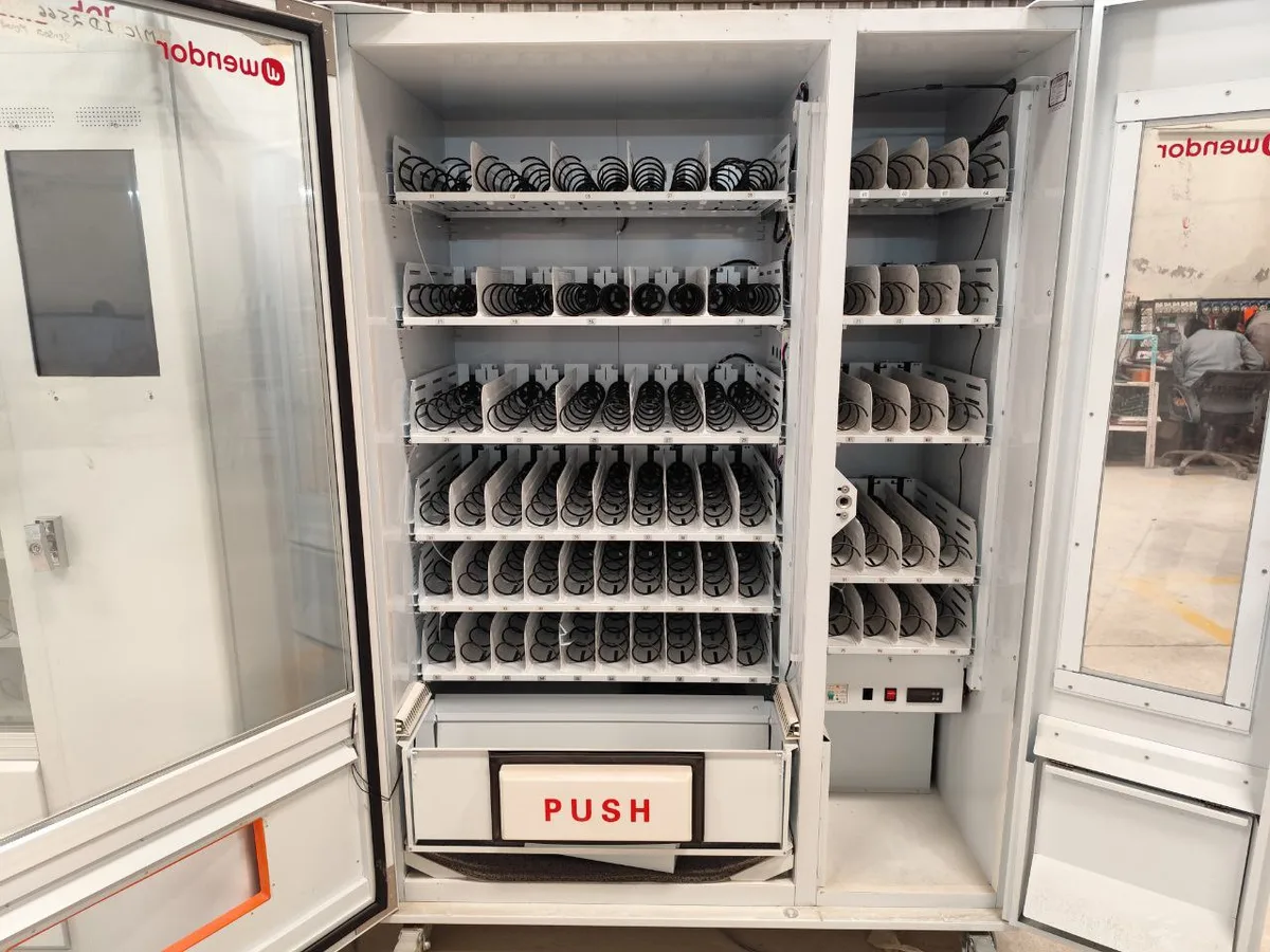 Operator manually rotating a spiral coil to free a stuck product in a snack machine.