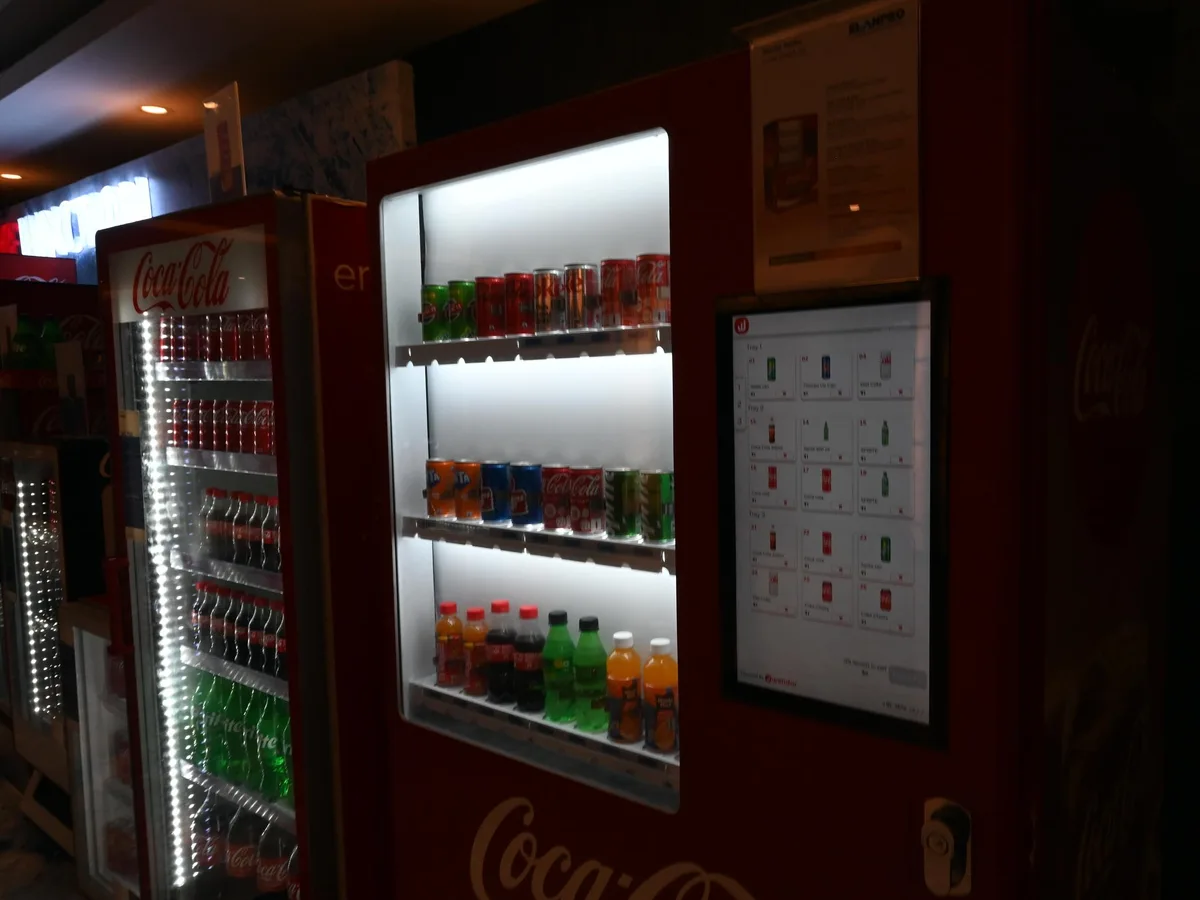 Operator inspecting and rebooting the cashless card and QR reader on a vending machine.