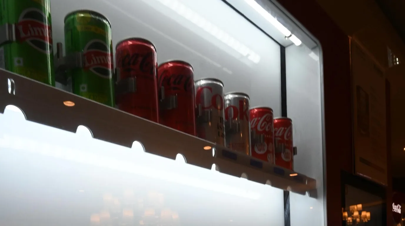 Health inspector checking the temperature and stock of a refrigerated vending machine.