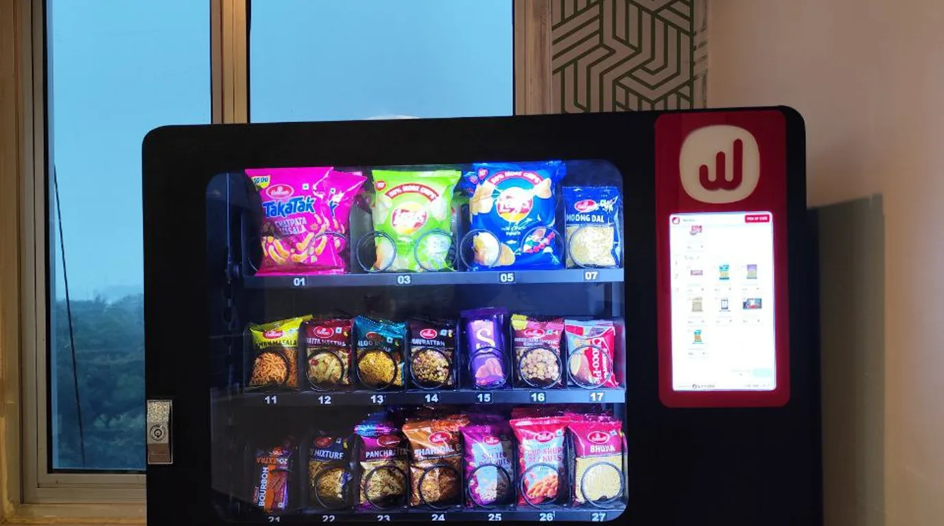 Person paying with a smartphone and smartwatch at a vending machine reader
