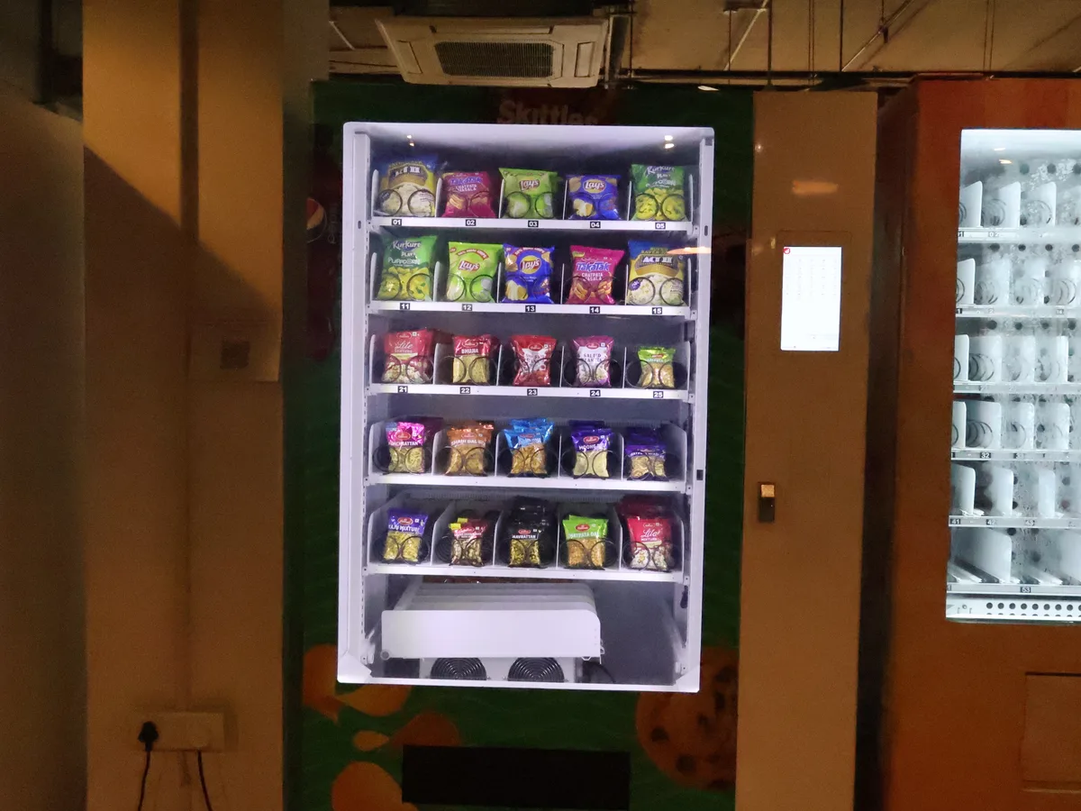 Operator restocking and cleaning a vending machine while checking sales data