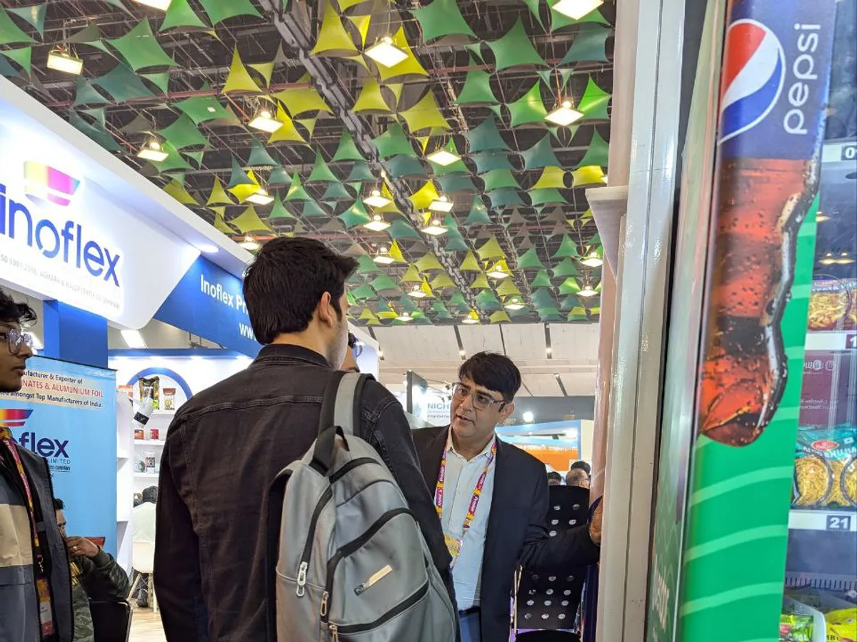 Hand holding a smartphone payment app in front of a vending machine