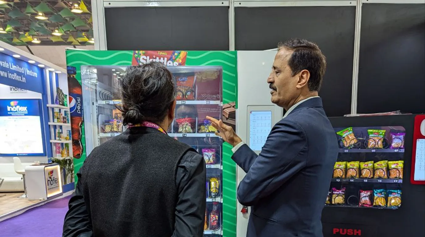 Hand holding a smartphone with a refund request screen near a vending machine