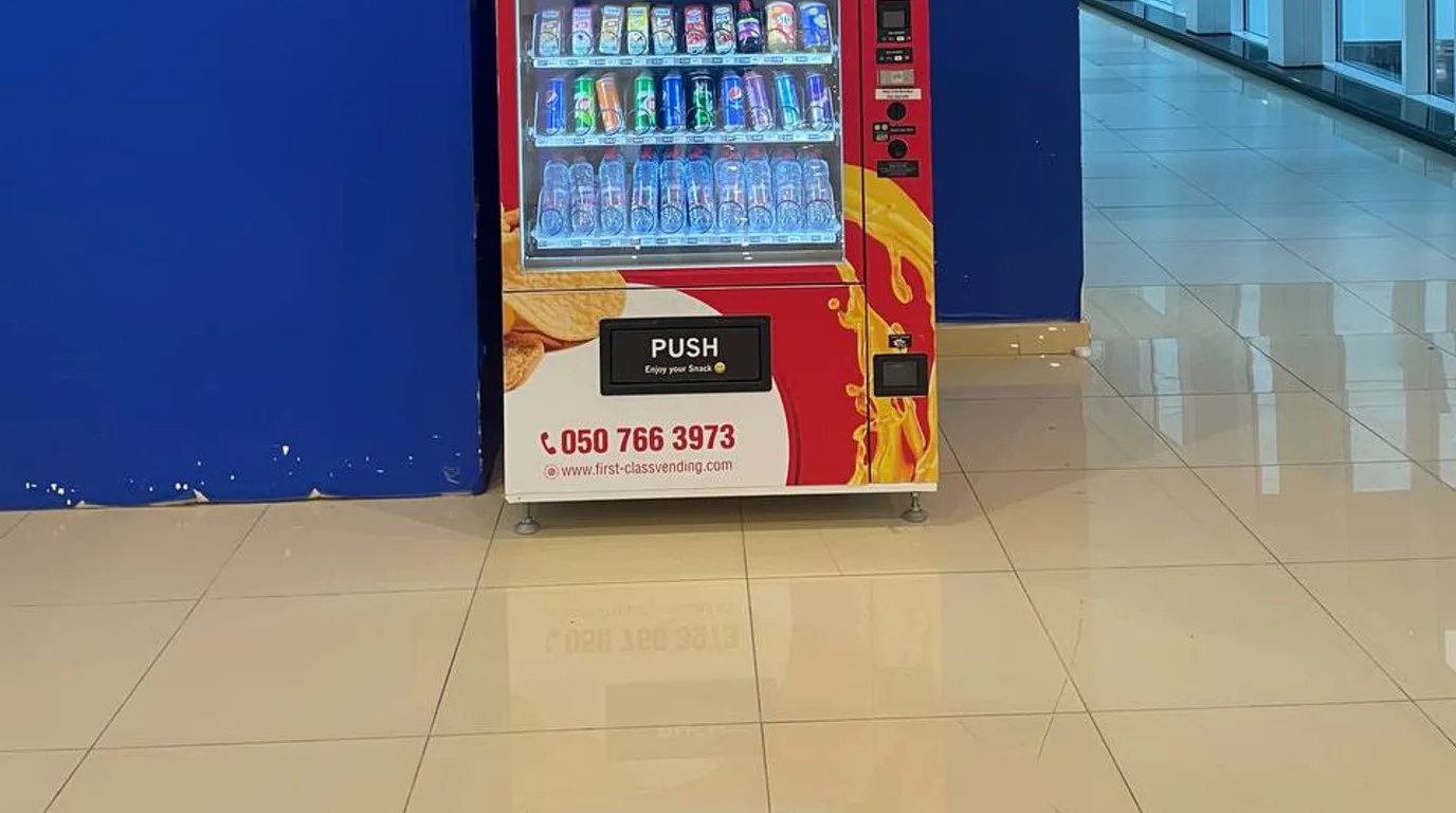Inspector reviewing a clean refrigerated vending machine in a Dubai lobby