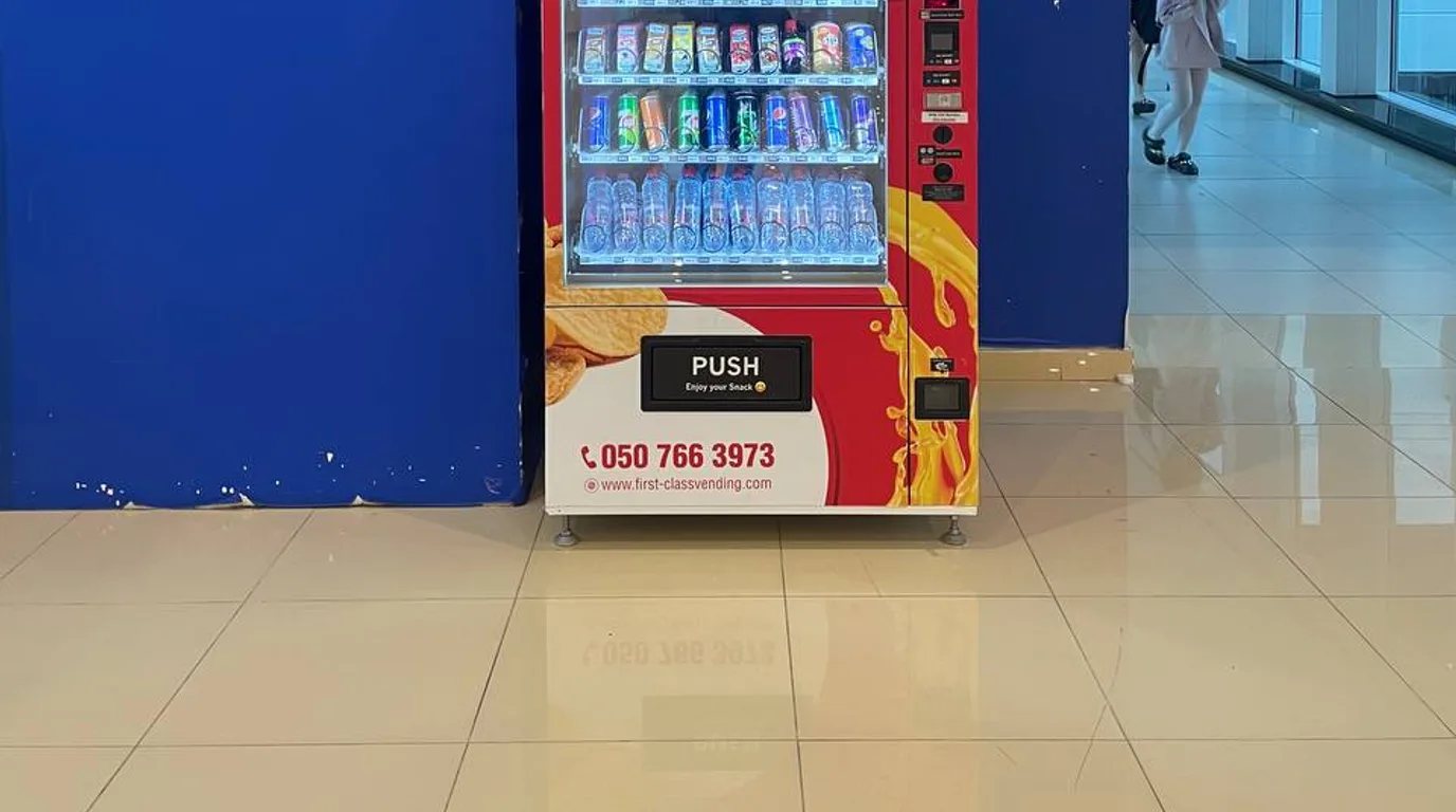 Tapping a phone to pay contactlessly at a modern vending machine in Dubai