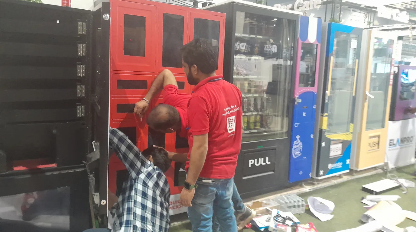 Operator inspecting the internal mechanism of a used vending machine before buying