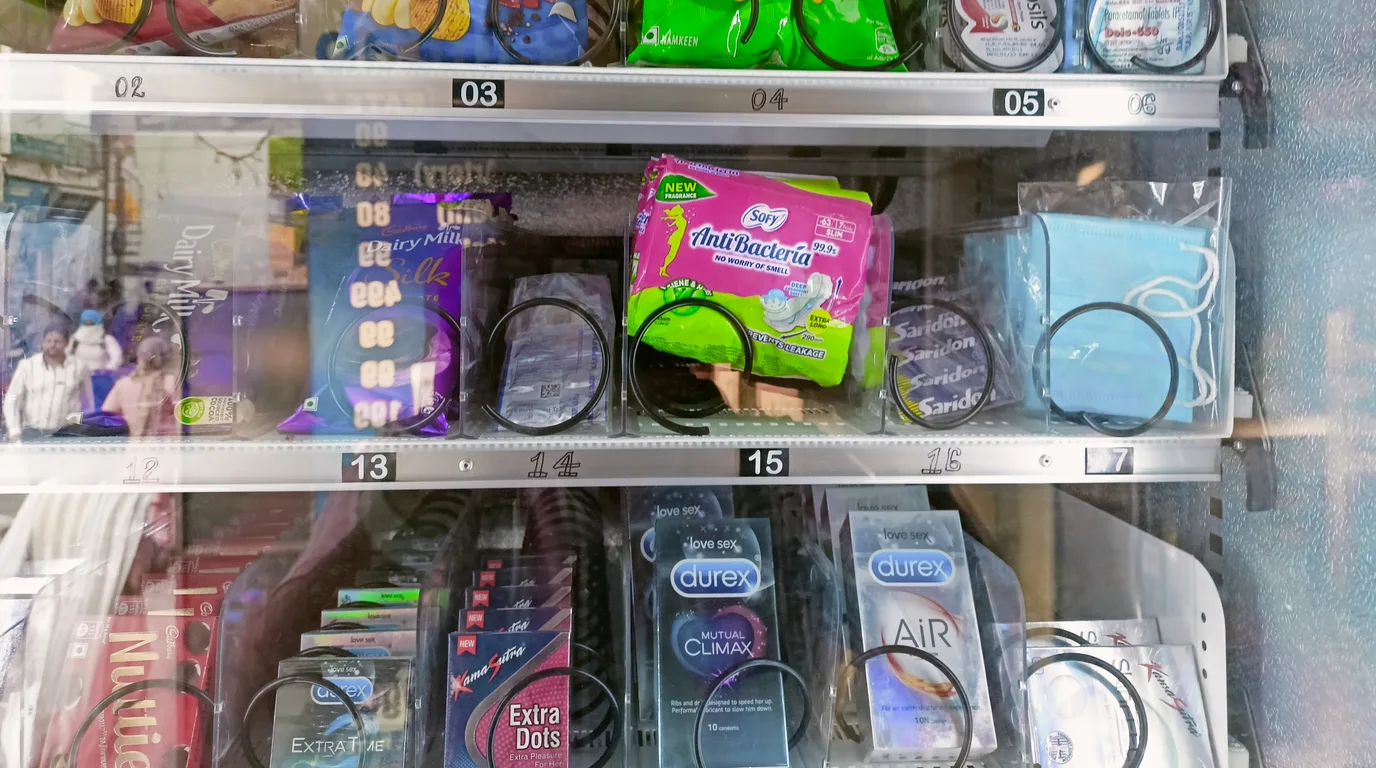 Worker wheeling cases of snacks from a delivery van toward a vending machine
