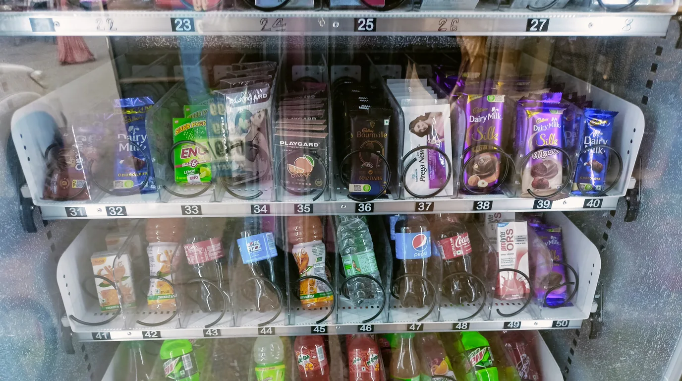 Phone showing a rising profit chart beside coins and a blurred vending machine
