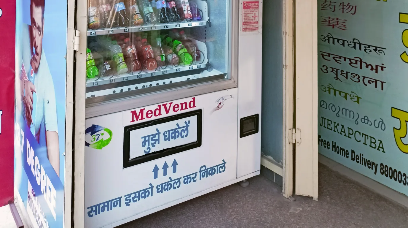 Hand collecting a snack from a vending machine as a coin drops in change