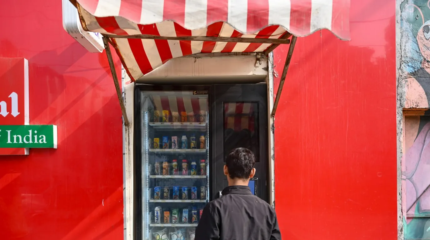 Hand pointing to a stocked slot inside an open vending machine with an error