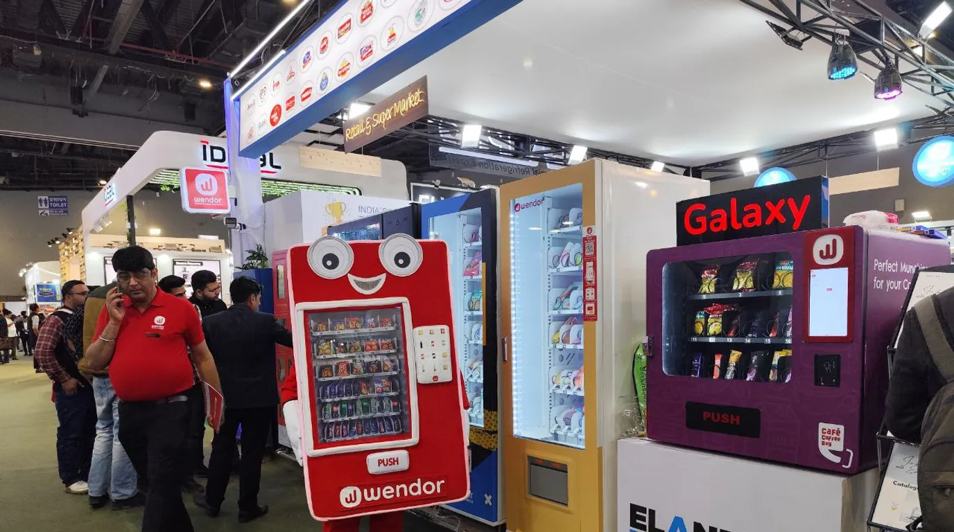 Device showing machine health gauges against a refrigerated office vending machine