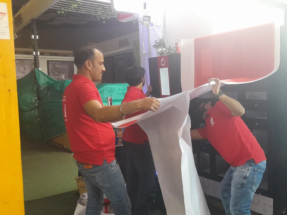 Staff member helping a hesitant first-time user operate a modern vending machine